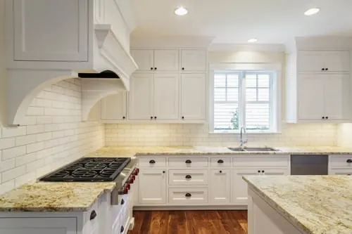 Completed kitchen renovation with white cabinetry, granite counters, and tile backsplash