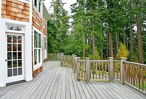 Newly built residential wood deck attached to a shingled home with railing