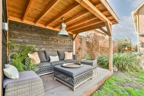 Covered outdoor living space with exposed wood ceiling, seating, and fireplace